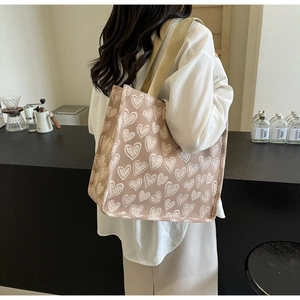 Dettagli della borsa tote in tela beige con motivi a cuore bianchi e tracolla larga