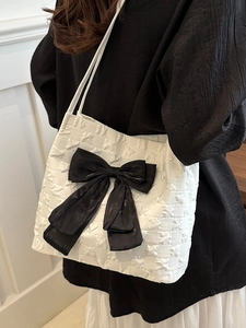 White bucket tote bag with star embossing and a large black silk bow detail