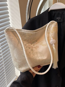 Elegante borsa a secchiello beige ricamata con motivi floreali e nappa di seta