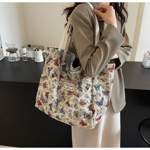 Detailed view of canvas tote bag featuring vibrant butterfly prints and wide shoulder straps