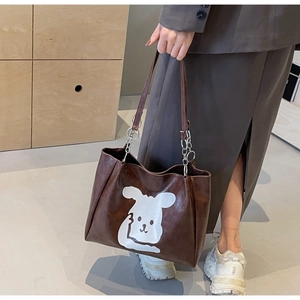 Close-up of brown cartoon tote bag featuring white rabbit print and metal chain strap