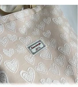 Detailed close-up of beige tote bag with embossed hearts and woven Nanaiaojie label