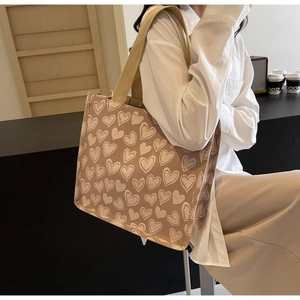 Dettaglio della borsa tote in tela beige con stampa a cuori e manico in fettuccia