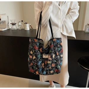 Close-up of black jacquard tote bag featuring colorful butterfly patterns and logo label