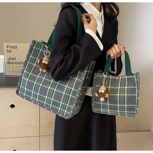 Macro shot of plaid canvas tote bags with green handles and cute monster charms