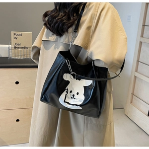 Detail of black tote bag with white cartoon graphic and silver metal chain strap detail