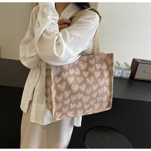 Dettaglio della borsa tote in tela marrone chiaro con cuori bianchi e ampia tracolla