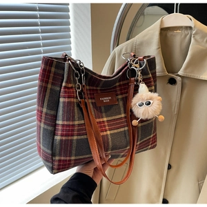 Detail of vintage plaid tote bag with brown leather handles and plush bear charm