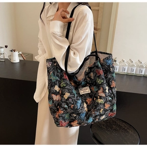 Detail of a large canvas tote bag with butterfly patterns and brand label on shoulder