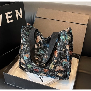 Detail shot of a black tote bag with colorful butterfly embroidery in a gift box setup