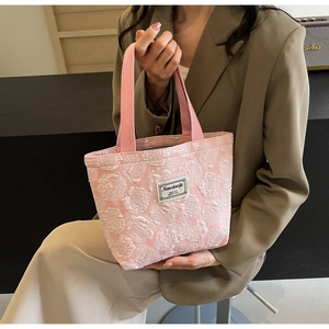 Detailed macro view of pink 3D rose jacquard fabric and brand label on tote bag