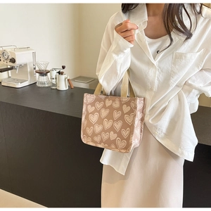 Dettaglio della borsa tote in tela marrone chiaro con stampe a cuore e manici intrecciati