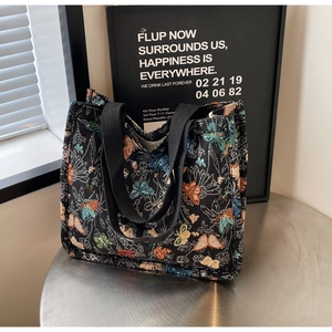 Close-up of the black jacquard tote bag featuring vibrant butterfly and floral embroidery