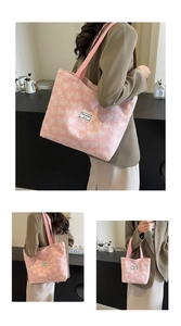 Detail of pink canvas tote bag showing white heart embroidery and woven strap handles