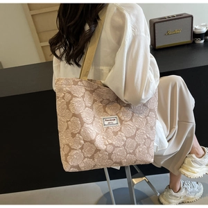Detail of vintage beige floral jacquard tote bag with textured rose patterns and woven strap