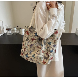 Detail of colorful butterfly prints on cream canvas tote bag with woven brand label