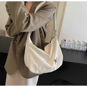 Détail du sac à bandoulière blanc en forme de croissant avec pendentif papillon argenté