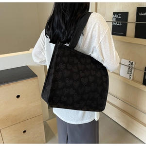 Dettaglio della borsa tote nera con trama a cuore e tessuto jacquard opaco moderno
