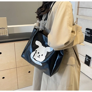 Close-up of black leather tote bag featuring a large white cartoon rabbit and chain strap