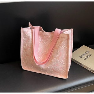 Gros plan du sac cabas rose montrant la texture florale en relief et les anses en tissu