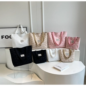 Close-up of heart-patterned canvas tote bags in four colors on a modern white display