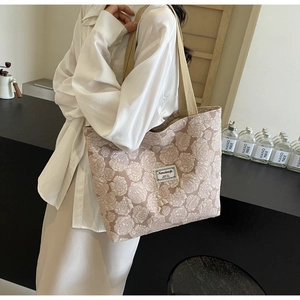 Detailed shot of rose embossed quilting texture and fabric branding on beige tote bag