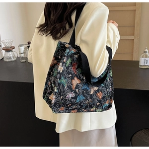 Detail shot of a large tote bag with vibrant butterfly jacquard on a black fabric base