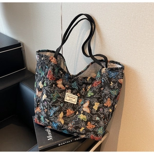 Detail of a black tote bag featuring colorful butterfly jacquard and decorative label