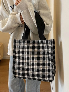 Minimalist black and white plaid tote bag shown at a 45-degree angle by a female model