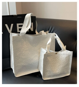 Detail view of large and small white tote bags with textured floral embossed pattern