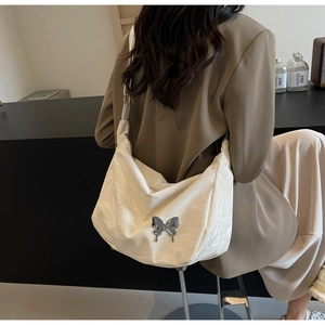 Détail du sac hobo crème avec texture froissée et boucle papillon argentée élégante