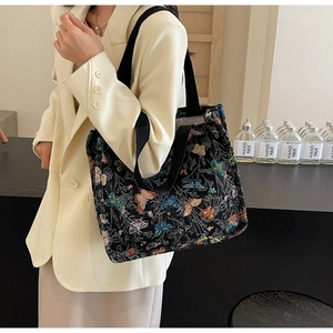 Detailed view of large black tote bag with butterfly embroidery and wide shoulder strap