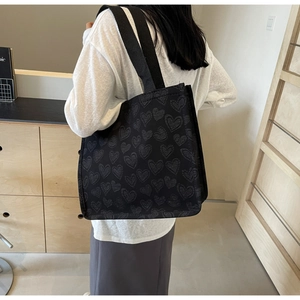 Dettaglio della borsa tote in tela nera con motivi a cuore bianchi e tracolle resistenti