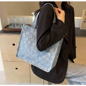 Detail of light blue tote bag with 3D floral texture and sturdy grey canvas handles