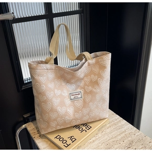 Close-up of pink tote bag with white heart jacquard pattern and woven label detail