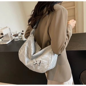Gros plan du sac plissé argenté métallisé avec une grande boucle papillon en métal