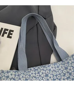 Détail du sac cabas en toile à fleurs bleues avec bandoulière tissée grise et couture