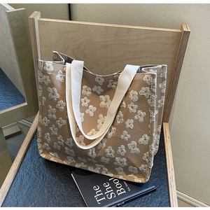 Close-up of brown canvas tote bag with white floral embroidery on a wooden chair