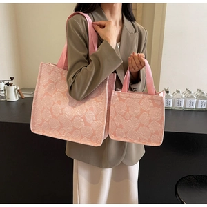 Détail de deux sacs cabas roses à motif jacquard rose tenus par un mannequin en studio