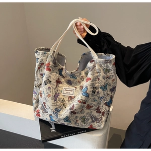 Detail of woven tote bag featuring colorful butterfly jacquard and branded fabric label