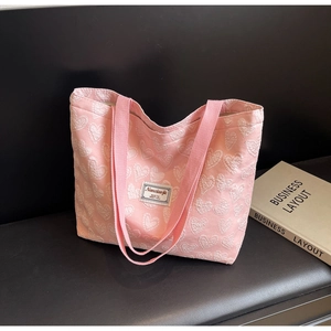 Close-up of pink tote bag featuring 3D heart jacquard fabric and vintage woven label