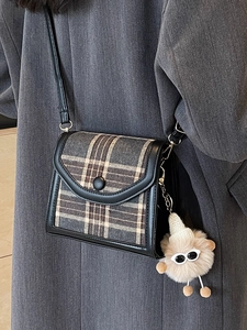 Vintage checkered flap crossbody bag with fuzzy monster charm worn by a model