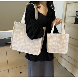Dettaglio del set borsa tote in tela beige con motivo jacquard a cuori bianchi