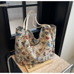 Detail of colorful butterfly print on thick canvas tote bag with woven texture and top handles