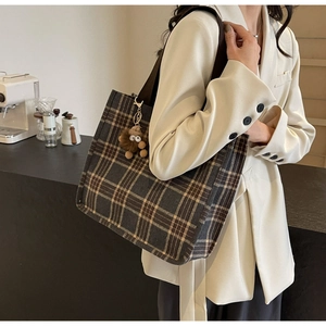 Detail of vintage plaid canvas tote bag with a brown plush charm in a cafe setting