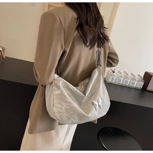 Détail du sac à bandoulière en croissant argenté avec plis métallisés et papillon