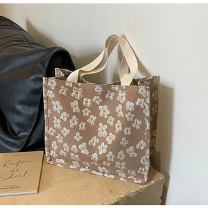 Detailed shot of brown canvas tote bag with 3D white flower embroidery and beige strap
