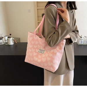 Detail of pink canvas tote bag featuring white heart embroidery and comfortable shoulder straps
