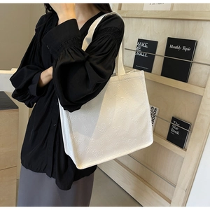 Close-up of white tote bag featuring unique embossed heart texture on leather surface