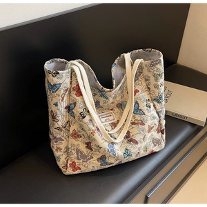 Detailed close-up of large canvas tote bag with colorful butterfly prints and brand label